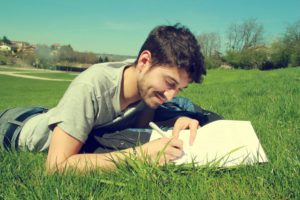 young man writing in field